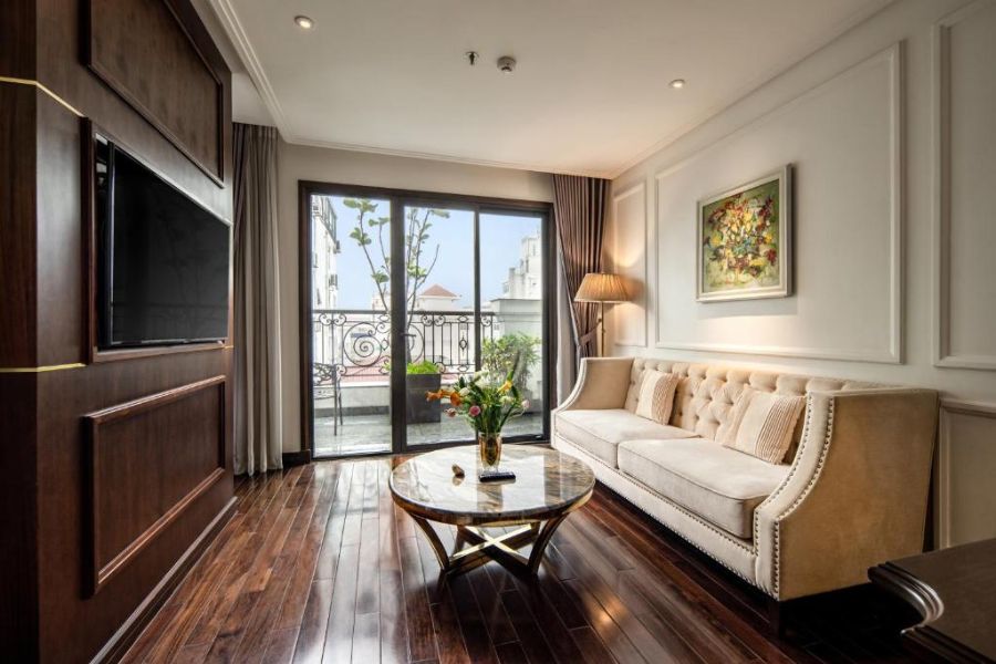 Sophisticated living area with tufted sofa, wooden floors, large TV, and balcony city views