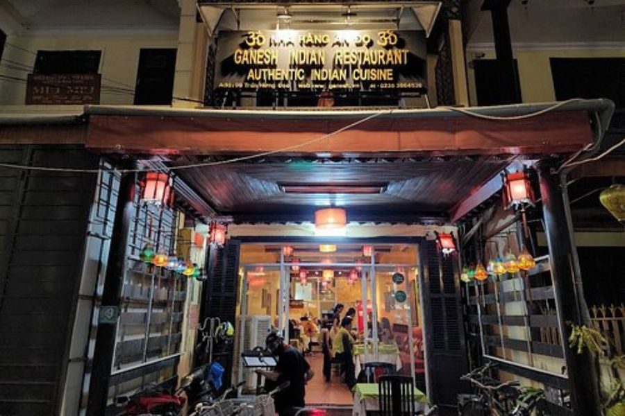 Exterior of Ganesh Hoi An Indian Restaurant at night with warm lights and signage