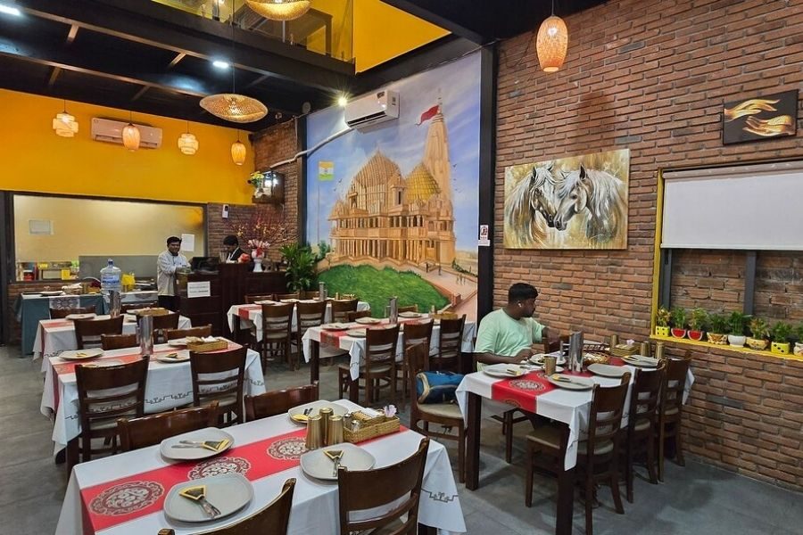 Gujarat Indian Restaurant interior with yellow walls, brick decor, wooden tables