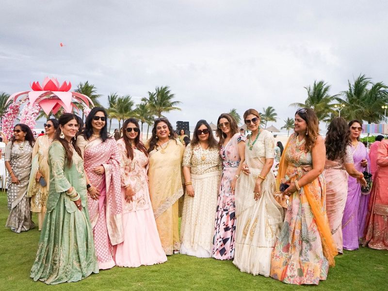 A group of Indian women in colorful traditional Saris and Lehengas posing at an outdoor wedding event in a coastal resort in Vietnam.