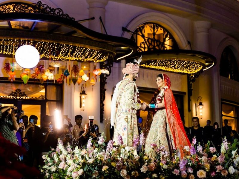 Indian couple at their wedding reception in Vietnam, decorated with traditional lanterns and elegant flower arrangements.