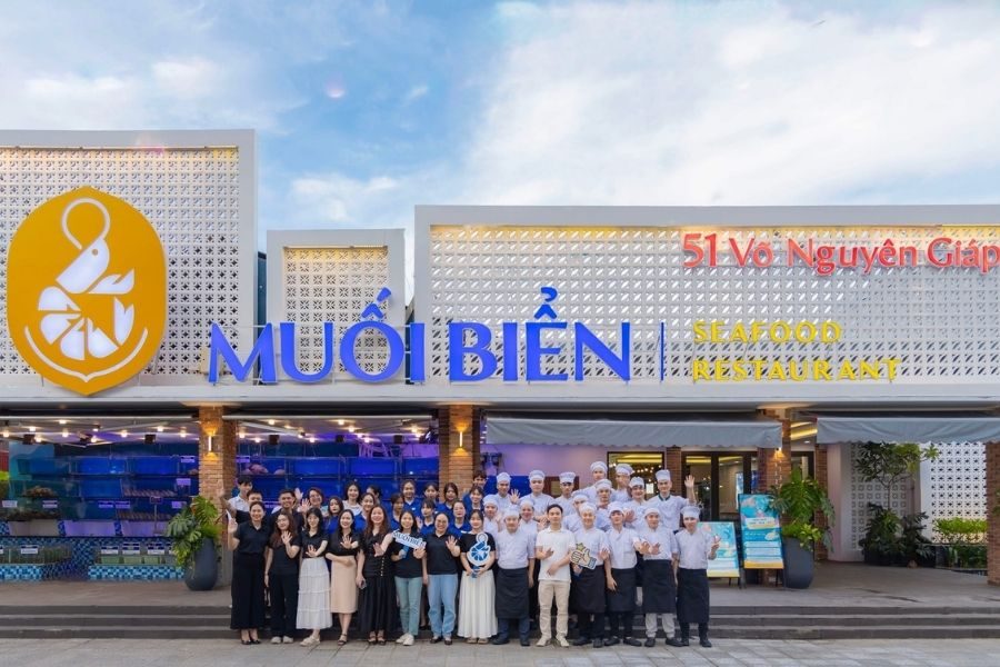 Muoi Bien Seafood Restaurant exterior with anchor logo, blue signage, and entire staff team photo at entrance