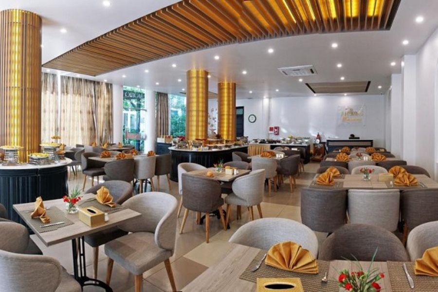 Modern dining area with gray chairs, golden napkins, wooden ceiling accents, and natural light