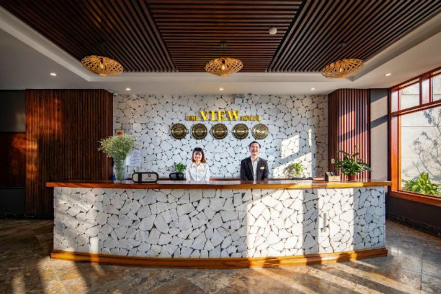 Modern reception desk with white stone wall, wooden accents, and friendly staff welcoming guests
