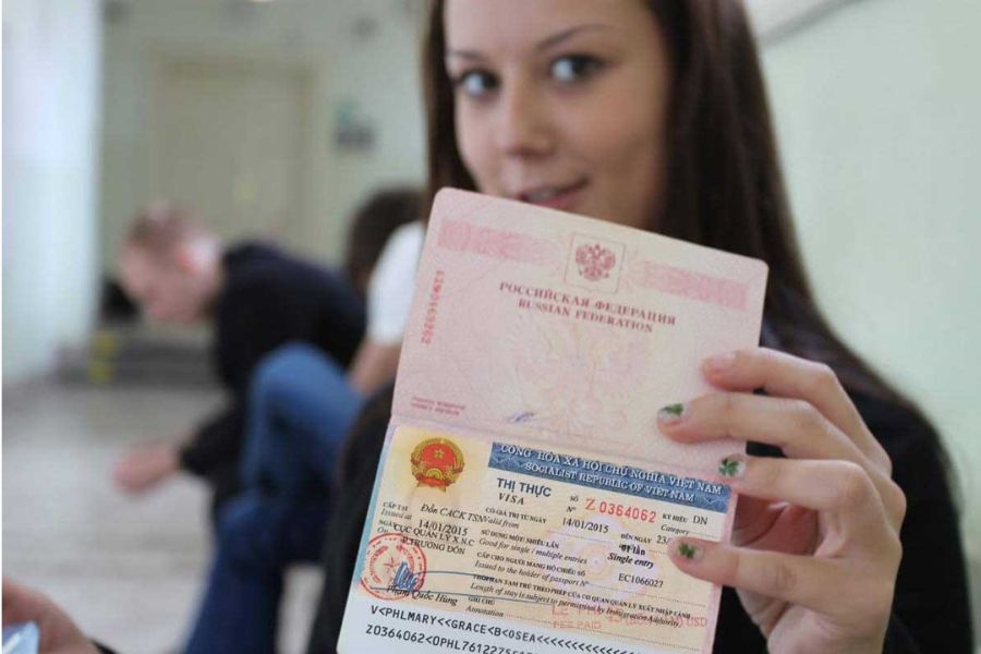 A happy female traveler holding her Russian passport with a stamped Vietnam entry visa inside