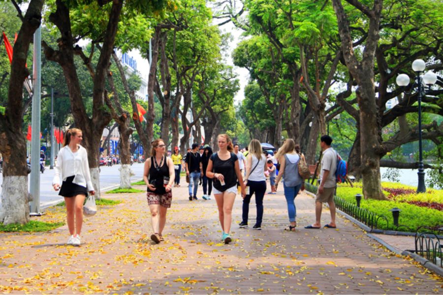 People walking under green trees by Hoan Kiem Lake