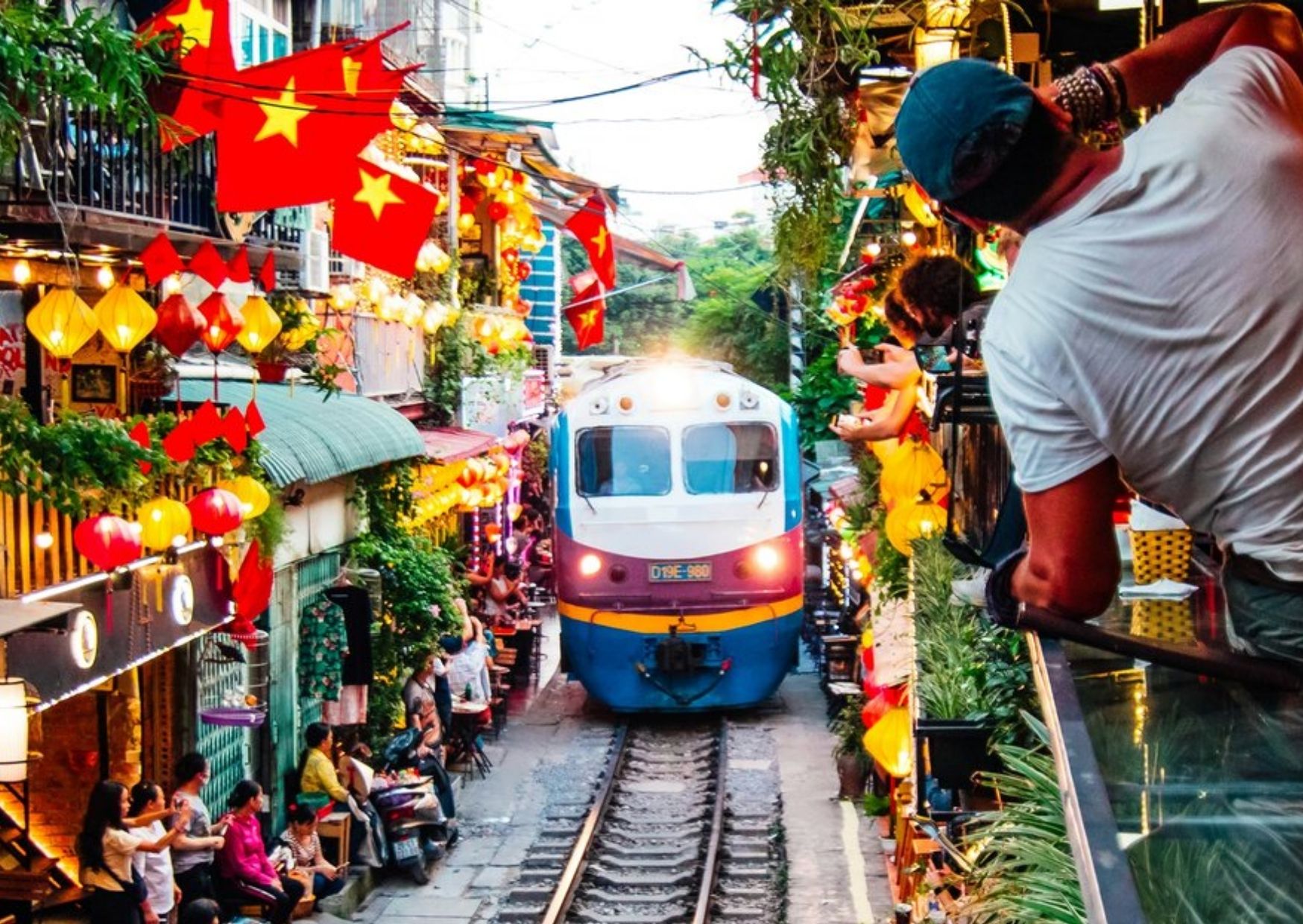 Train passing through Hanoi Train Street with lanterns