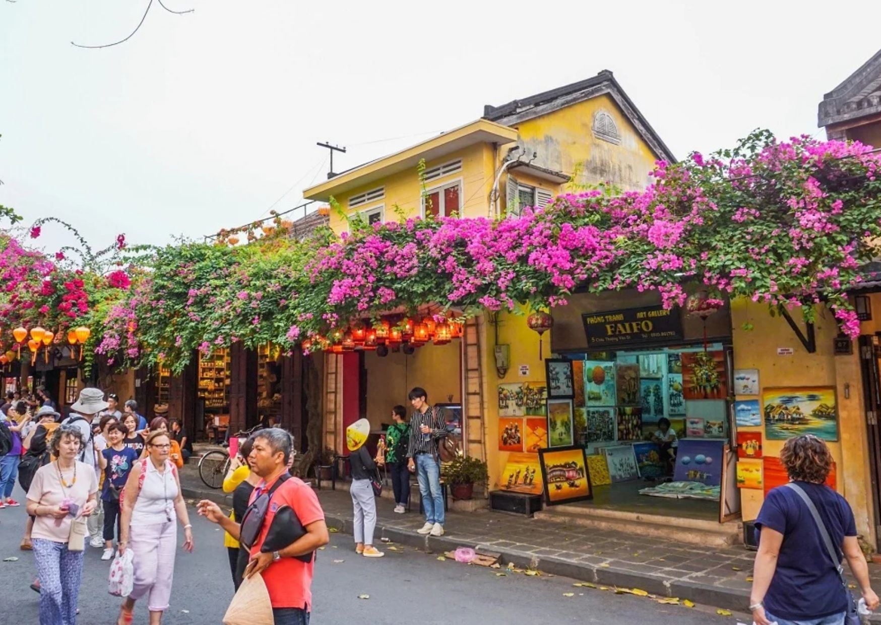 People walking in Hoi An Ancient Town with bougainvillea