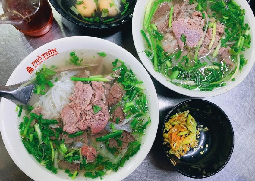 Two bowls of Vietnamese beef pho topped with fresh green onions