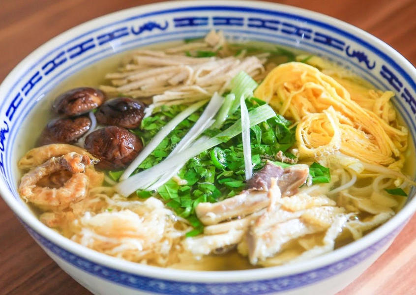 A bowl of traditional bun thang noodles with colorful toppings