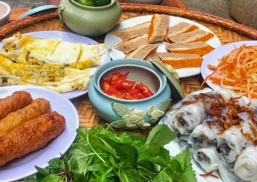A platter of Vietnamese steamed rice rolls with sides and herbs