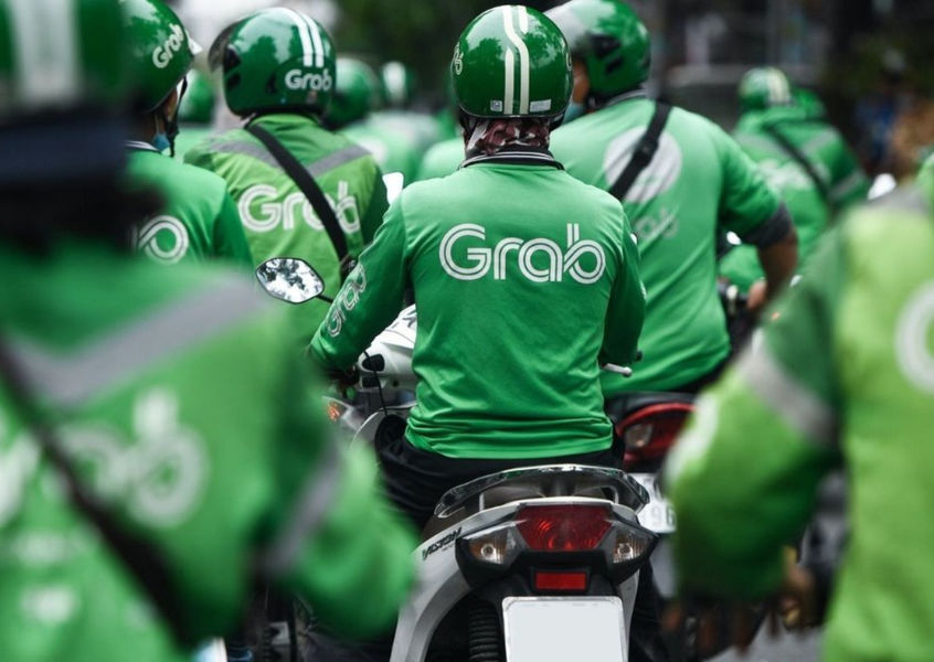 Grab motorbike taxi drivers in green uniforms on street in Vietnam