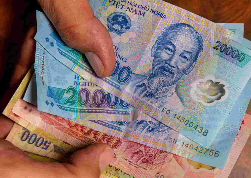 Hand holding Vietnamese dong banknotes including 20000 VND bills