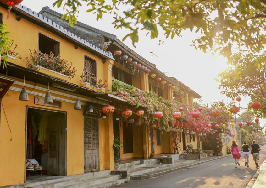 Sunlit street in Hội An Ancient Town lined with yellow colonial buildings and red lanterns