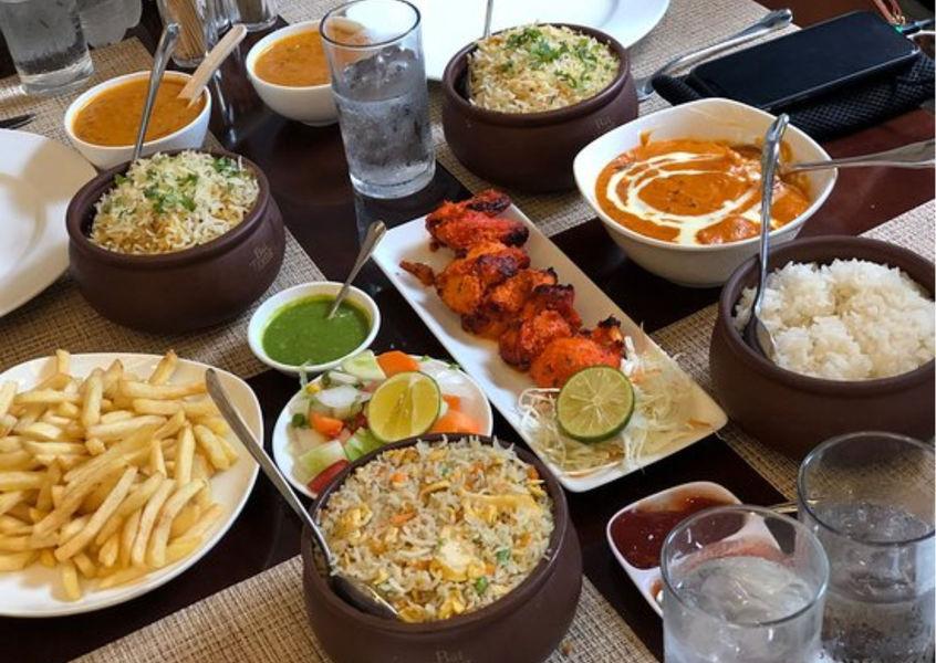 Indian meal spread with chicken tikka, rice, and fries