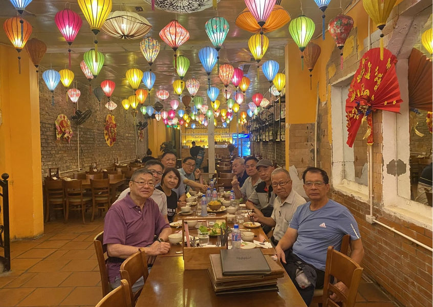 Group of people sitting under colorful lanterns in restaurant