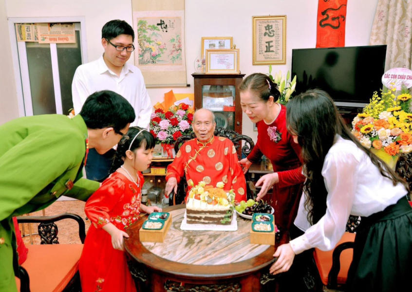 Multi-generational Vietnamese family gathering around an elder during a celebration