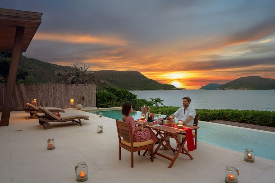 Couple dining at sunset by pool overlooking Con Dao bay