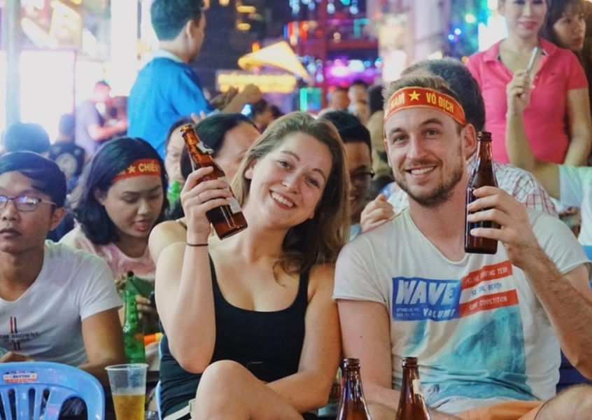 Foreign couple holding beer at Vietnam street festival