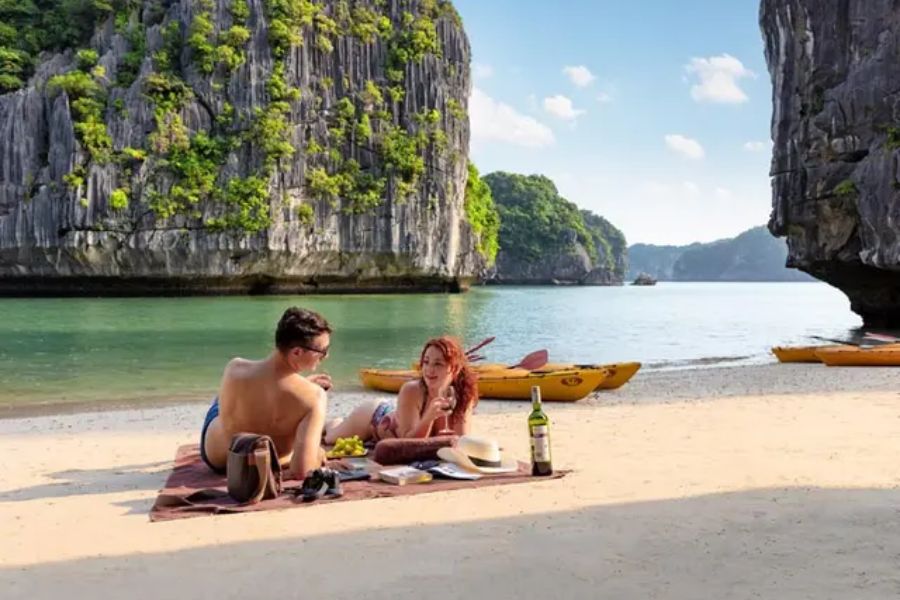 Couple picnicking on beach among Halong Bay limestone cliffs