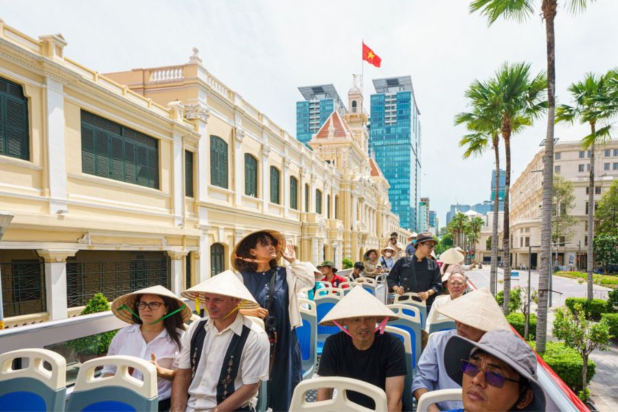Tourists on open-top bus tour past Ho Chi Minh City landmarks