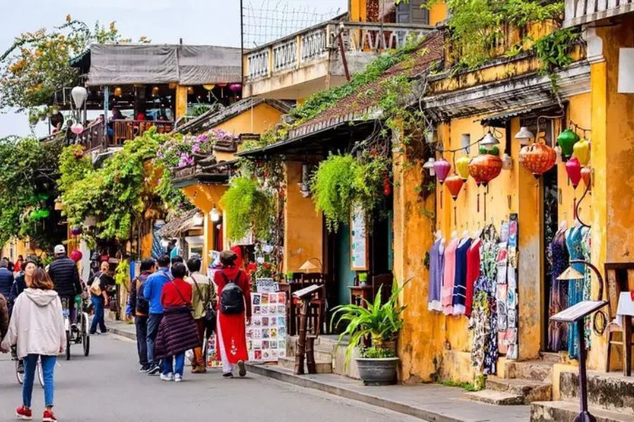 Tourists strolling Hoi An old town street with yellow houses