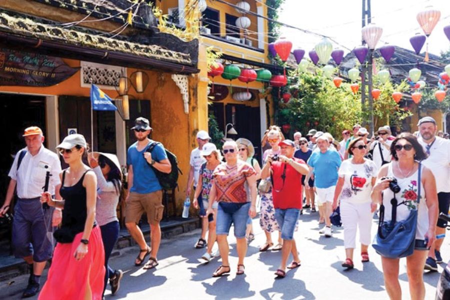 Crowded tourists walking Hoi An lantern street in peak season