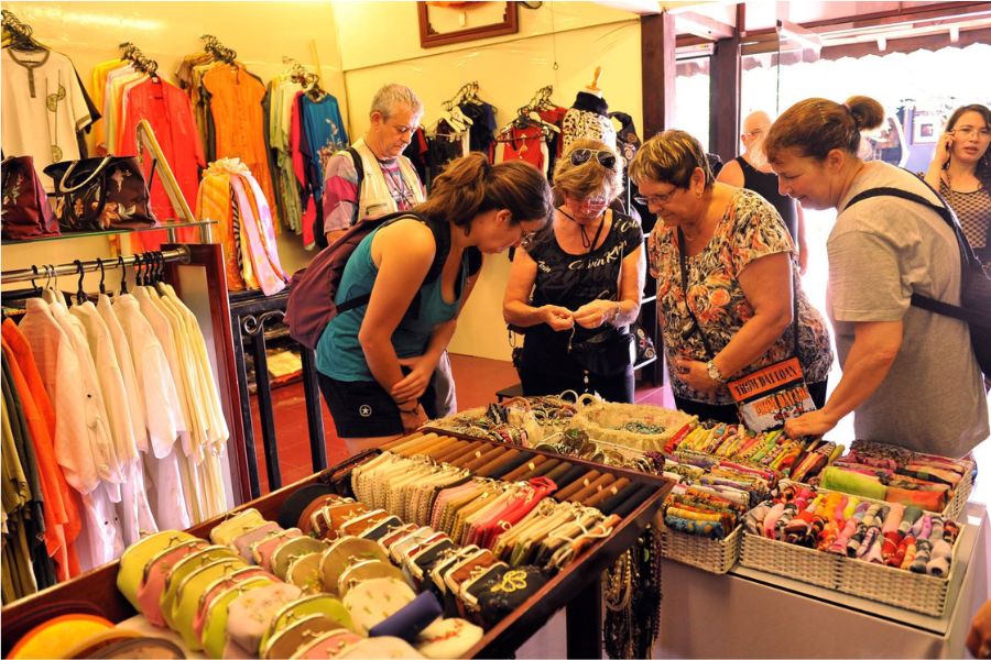 Tourists browsing silk scarves and souvenirs at a Hoi An shop