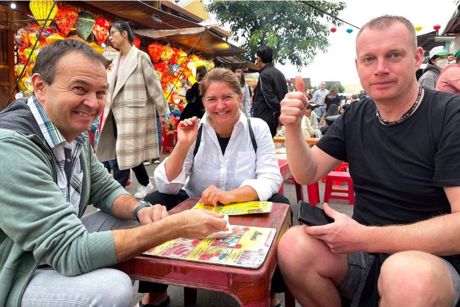 Travelers giving a thumbs up at an outdoor table in Hoi An's lantern street