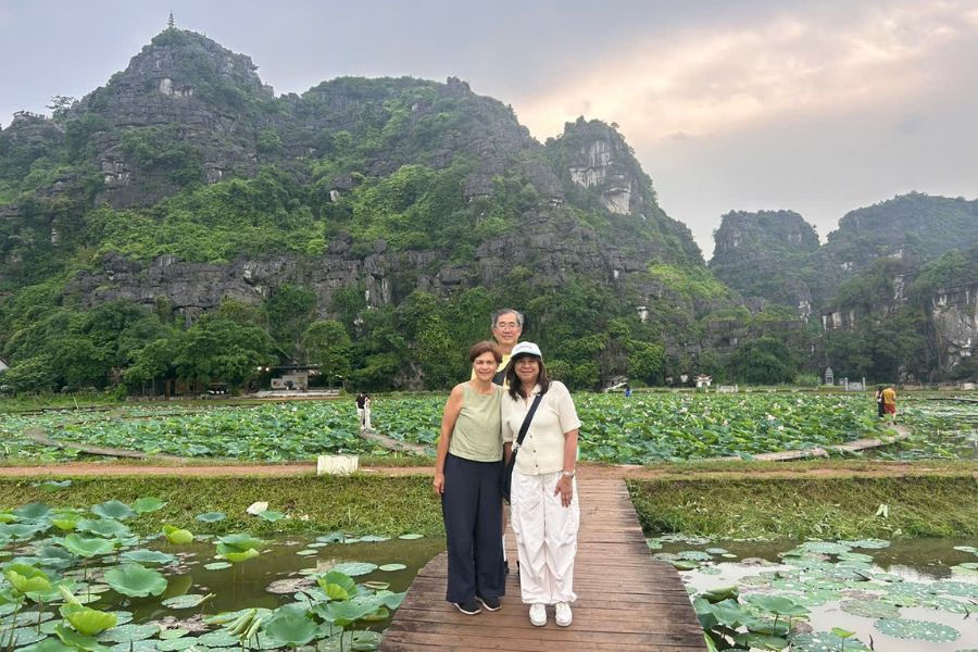 Couple walking a wooden path through Ninh Binh's lotus fields