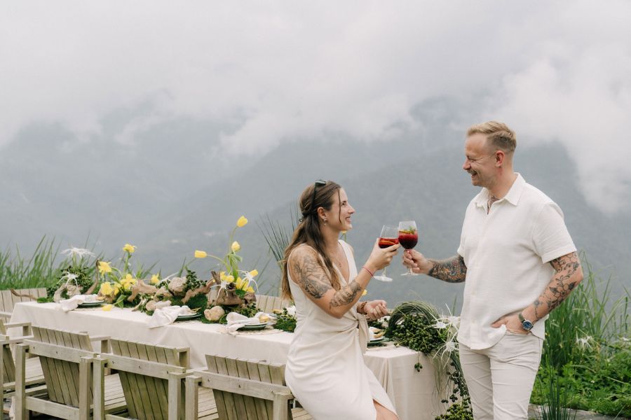 Couple toasting wine at outdoor table in misty Sapa mountains