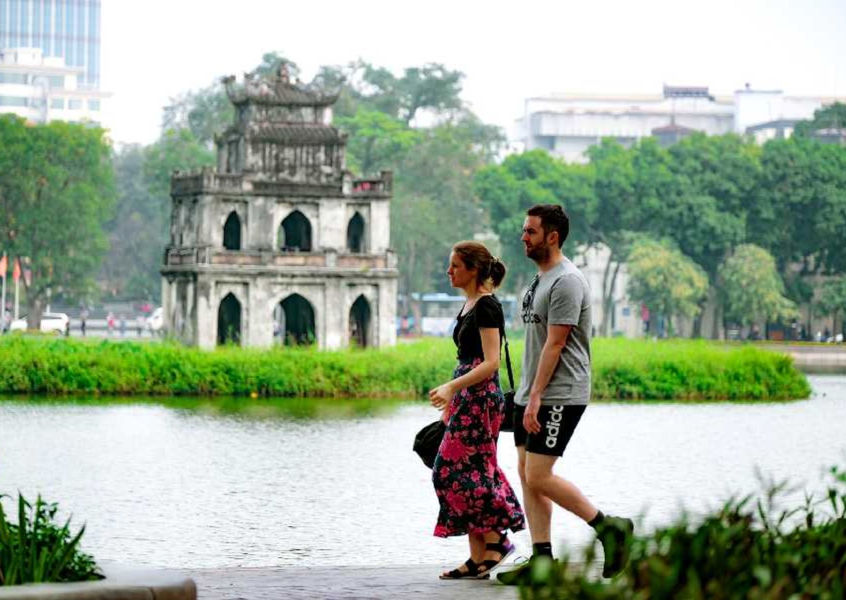 Couple walking near Hoan Kiem Lake Turtle Tower, Hanoi
