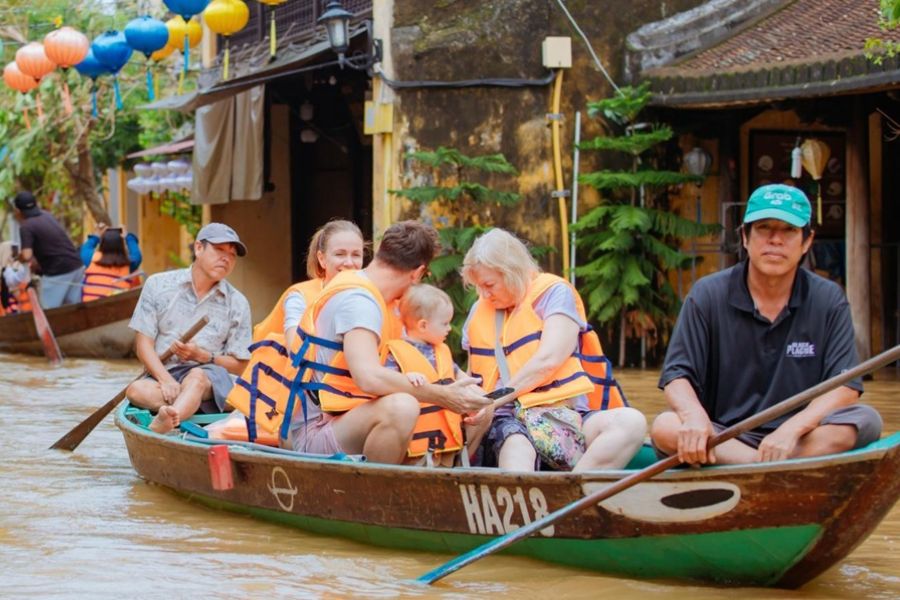 Tourists wear life vests on a boat through flooded Hoi An street