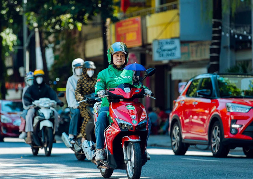 Grab motorbike taxi driver riding through Hanoi traffic