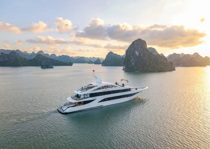 Luxury cruise ship sailing through Ha Long Bay at sunset
