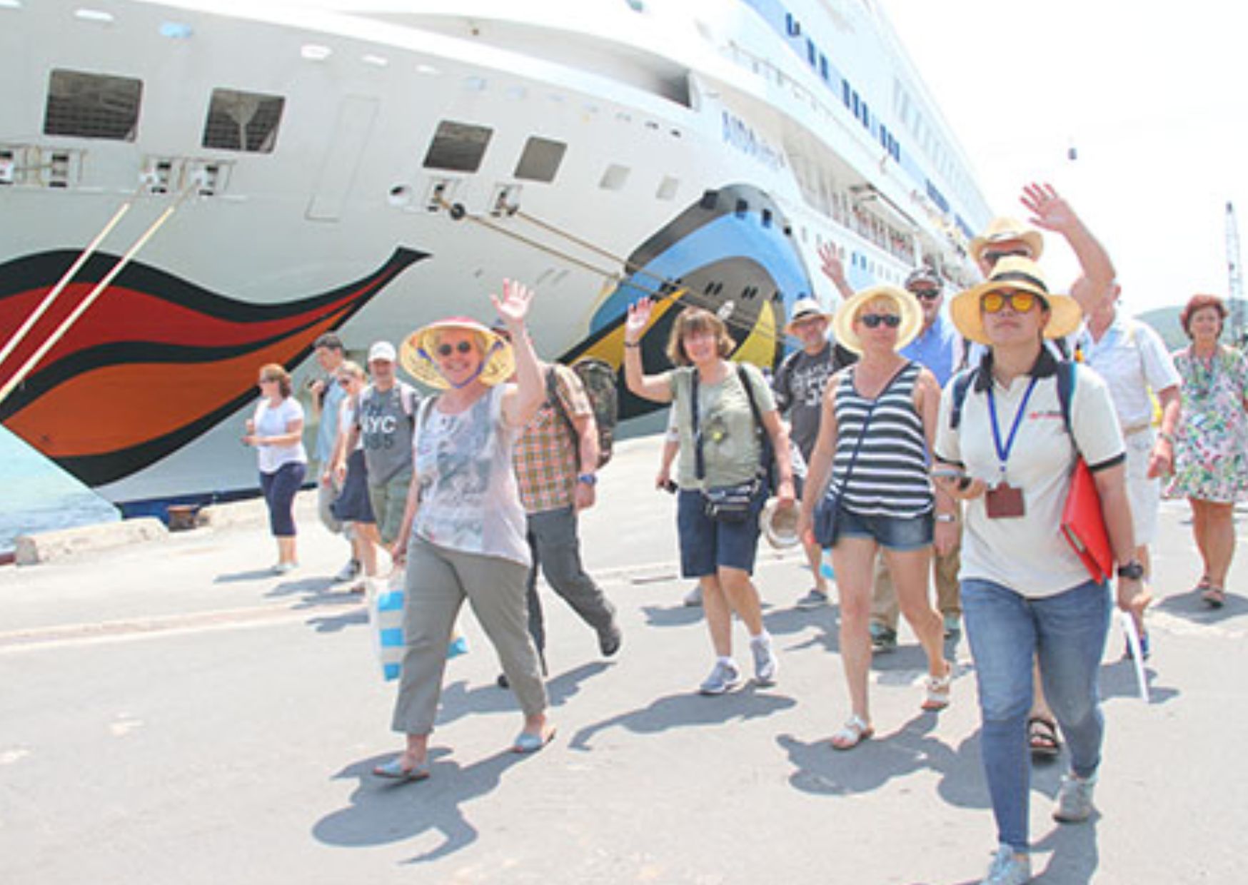 Tourists waving while disembarking a cruise ship at dock