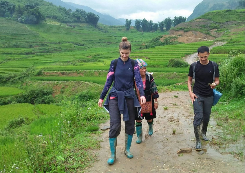 Tourists trekking a muddy trail with a local guide, Sapa