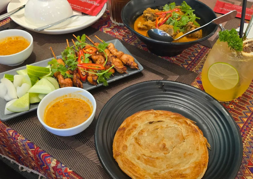 Satay skewers, curry, and flatbread on a patterned tablecloth