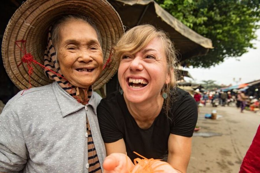 Tourist sharing a joyful greeting with an elderly Vietnamese woman