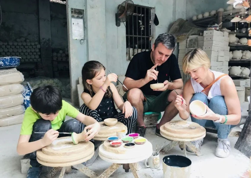Family painting handmade pottery bowls at a ceramic workshop in Bat Trang Village
