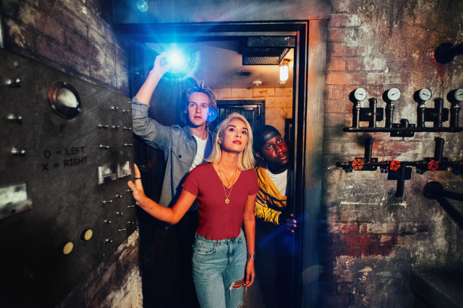 Three teammates solving puzzles in an escape room
