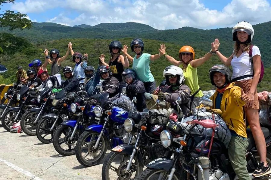 Group motorbike tour riders posing on hillside road, Vietnam