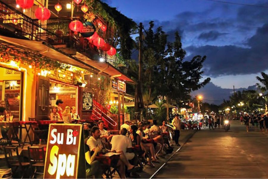 Lantern-lit cafes along a Hoi An street at dusk