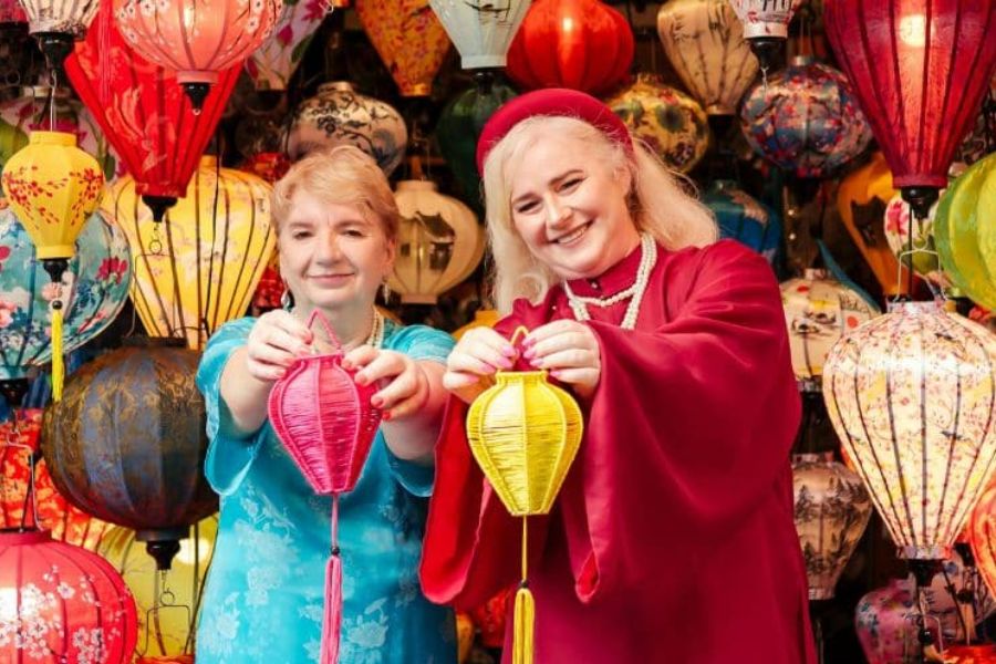 Two travelers holding handmade silk lanterns at a Hoi An lantern-making shop