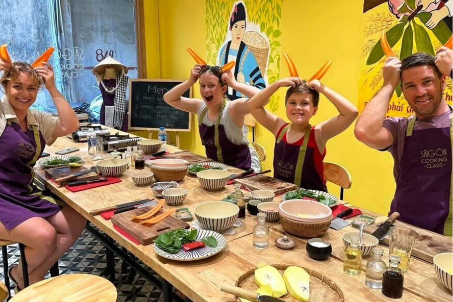 Team in aprons holding carrots at a Saigon cooking class