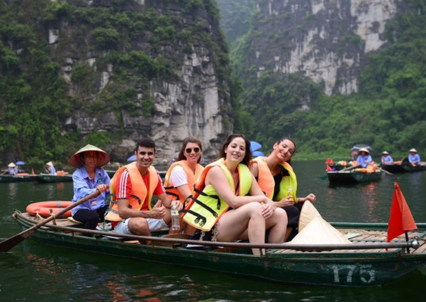 Tourists in life jackets riding a traditional sampan boat in Ninh Binh